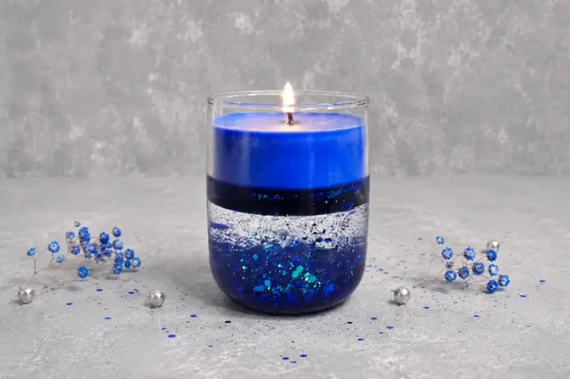 Vela en agua azul en recipiente de vidrio